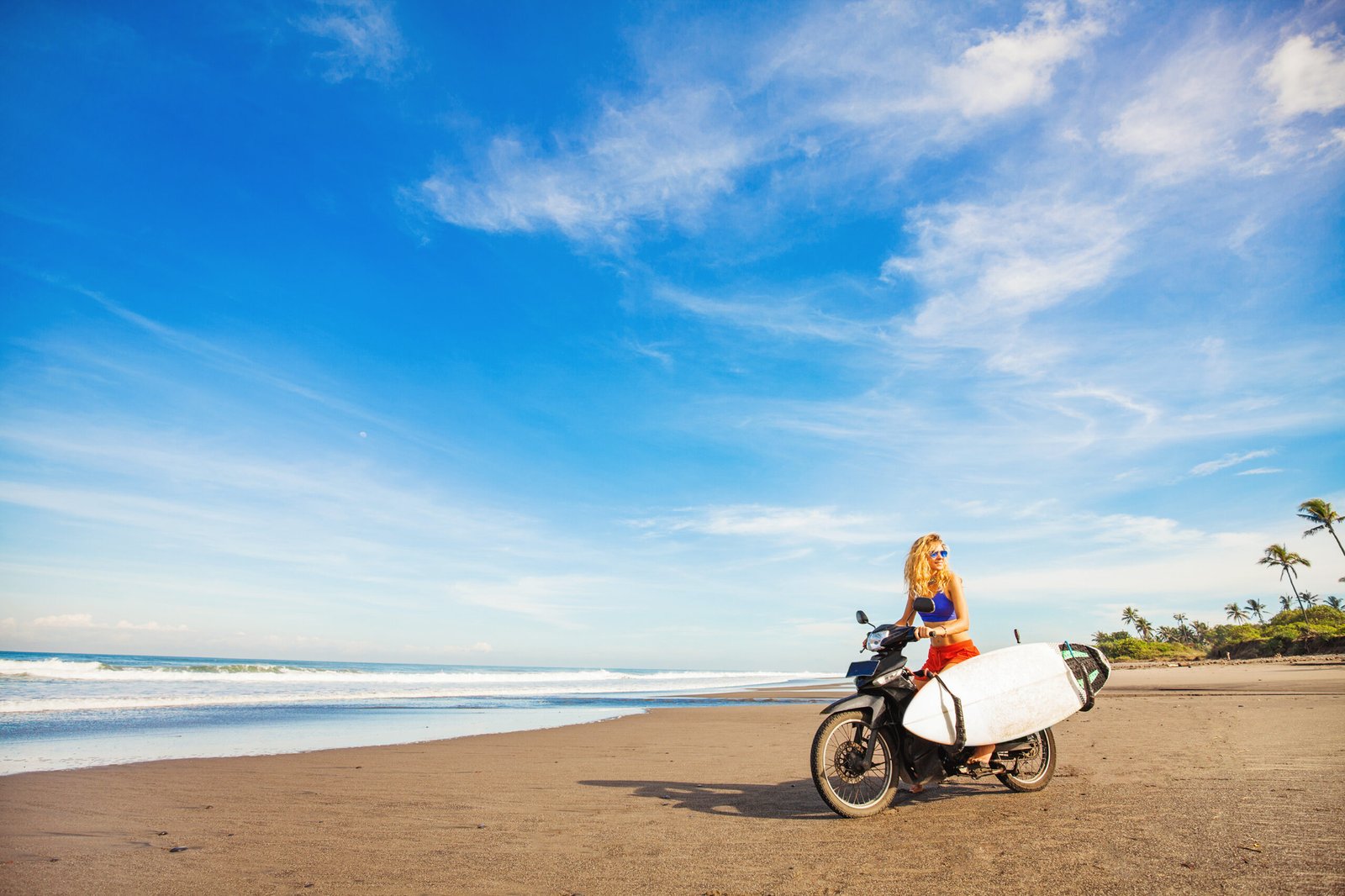 Services wonderful trip woman riding a motorcycle with the surfboard